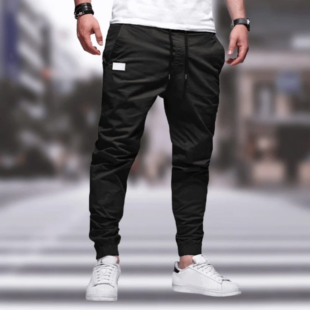 Mann in schwarzer Jogginghose und weißen Sneakers auf Straße, sportlich, urbaner Stil.