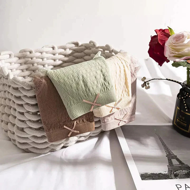 Geflochtener Korb mit bunten Handtüchern, rote Rose in Vase, Eiffelturm-Foto, dekorativ.