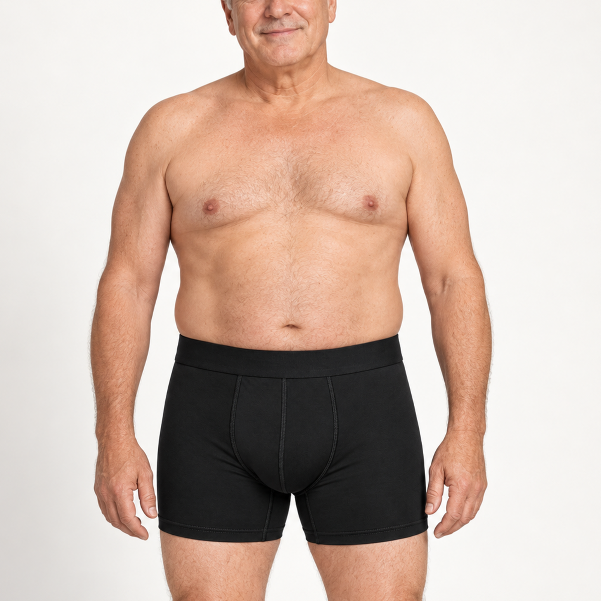 Äldre man med bar överkropp står rakt framifrån i svarta boxerkalsonger med längre ben och bred midjelinning. 2