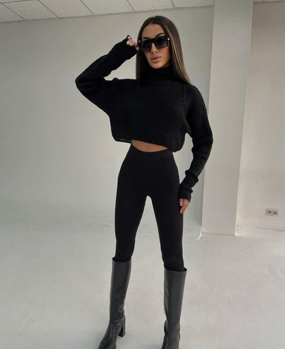 Frau in schwarzem Strickpullover, Leggings und Stiefeln, trägt Sonnenbrille, modisches Outfit.