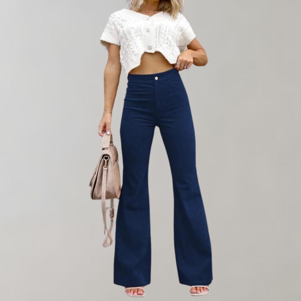 Frau in blauer Schlaghose und weißem Crop-Top, hält beige Tasche, modisch, elegant.