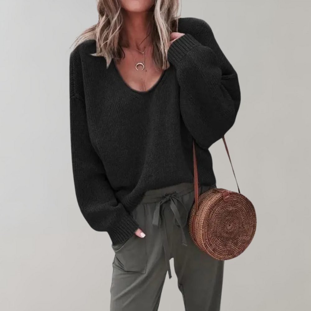 Frau in schwarzem Pullover mit runder Strohtasche und grauer Hose, modisch, lässig.