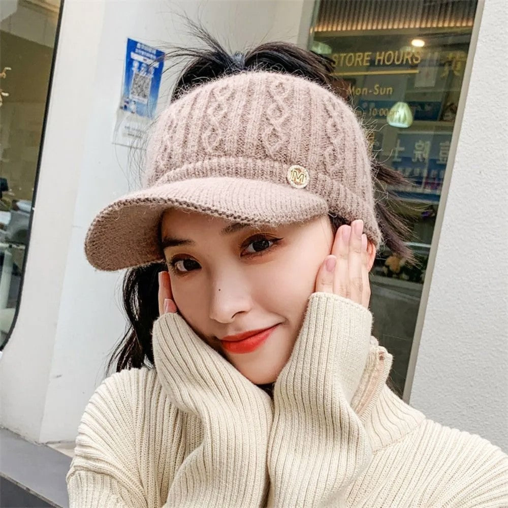 Frau mit beigem Strick-Visor, lächelt, trägt cremefarbenen Pullover, modisch, Herbstmode.