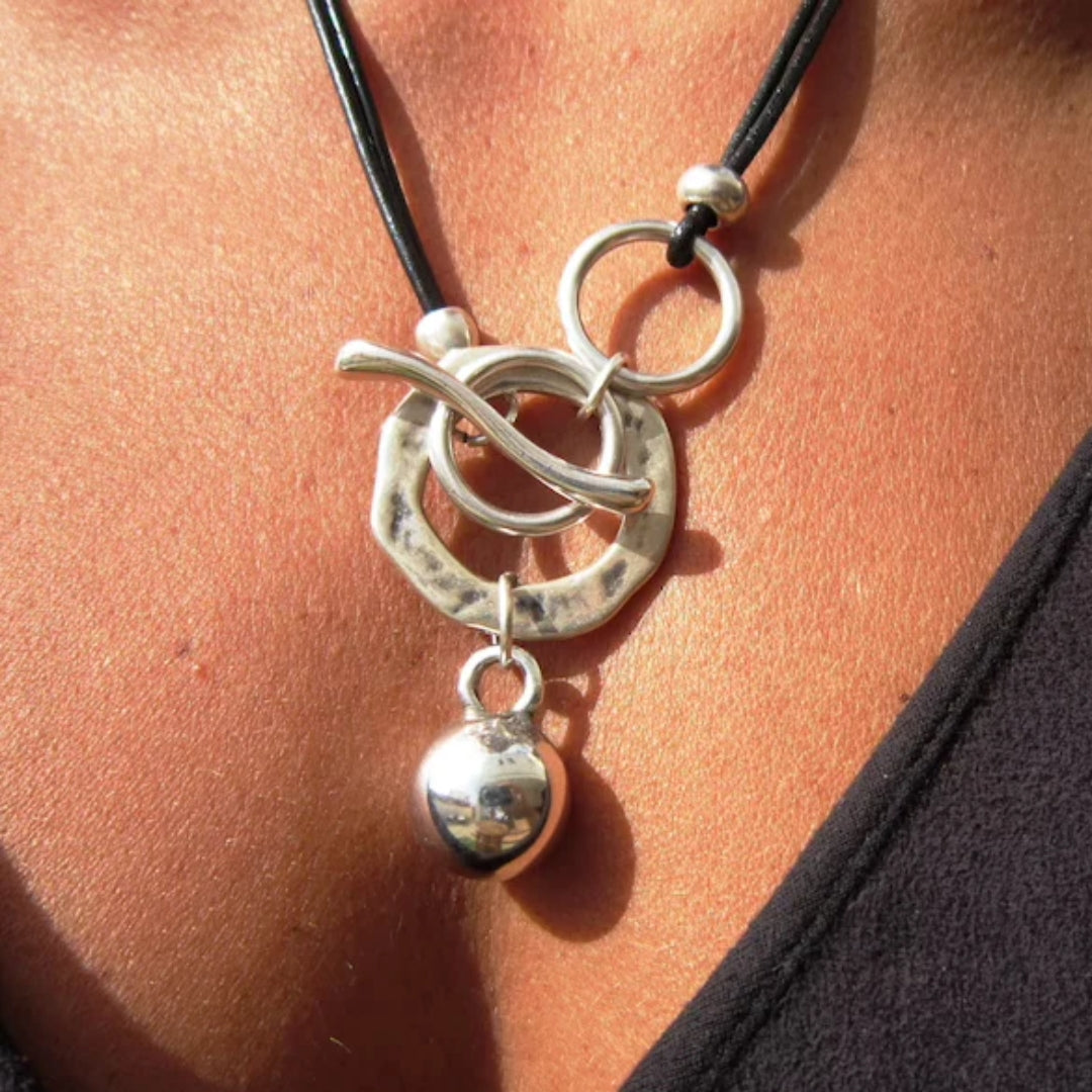 Silberner Anhänger an schwarzem Lederband, modernes Design, handgefertigter Schmuck.