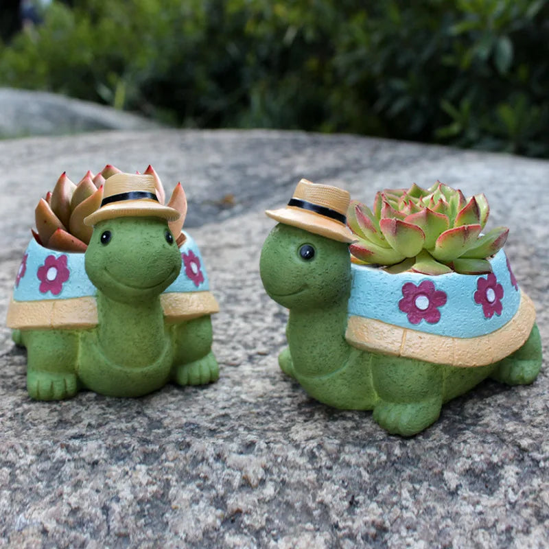 Zwei grüne Schildkröten-Blumentöpfe mit Hüten und Sukkulenten, Garten-Dekoration.