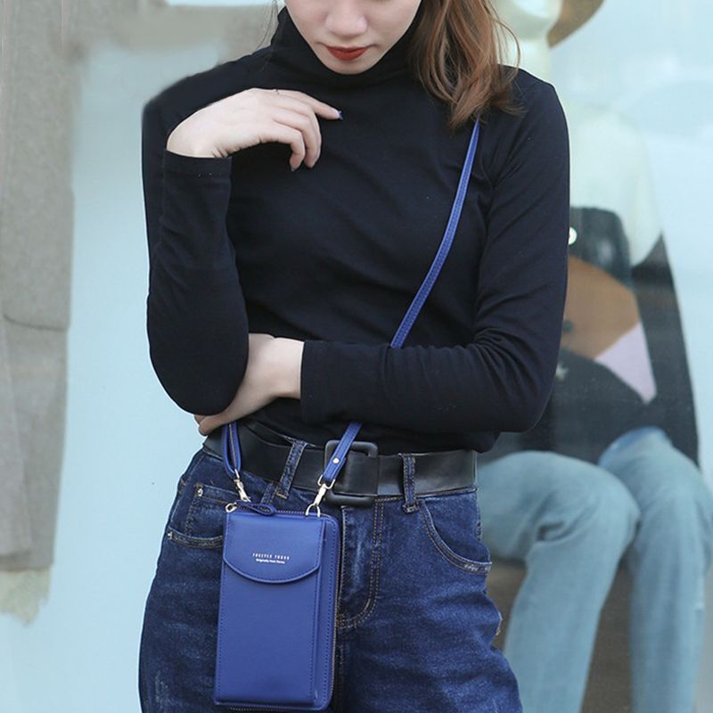 Frau mit blauem Handy-Umhängetasche, schwarzem Rollkragenpullover und Jeans.