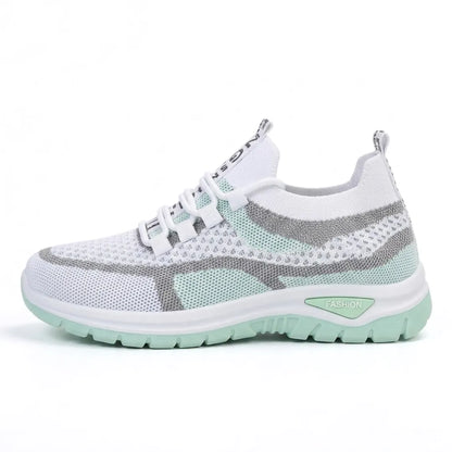 Sidovy av vit sneaker i mesh med mintgröna och grå partier och mintgrön sula, mot vit bakgrund. 10