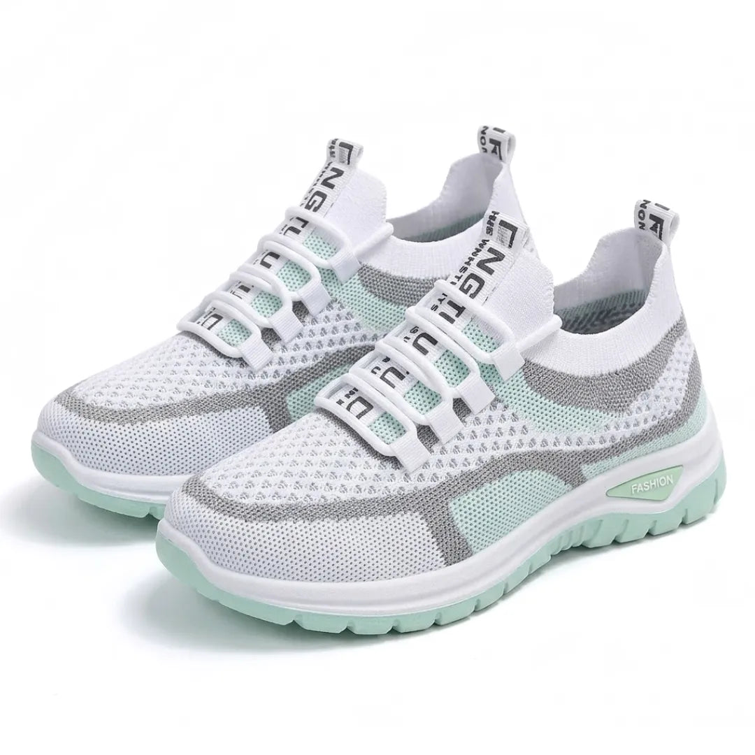 Ett par vita och mintgröna mesh-sneakers med snörning och grön sula, snett framifrån mot vit bakgrund. 16