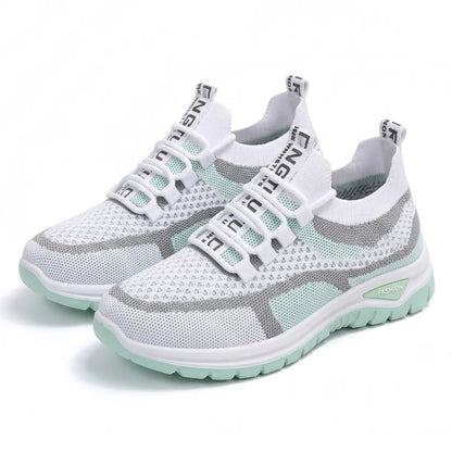 Ett par vita och mintgröna mesh-sneakers med snörning och grön sula, snett framifrån mot vit bakgrund. 16