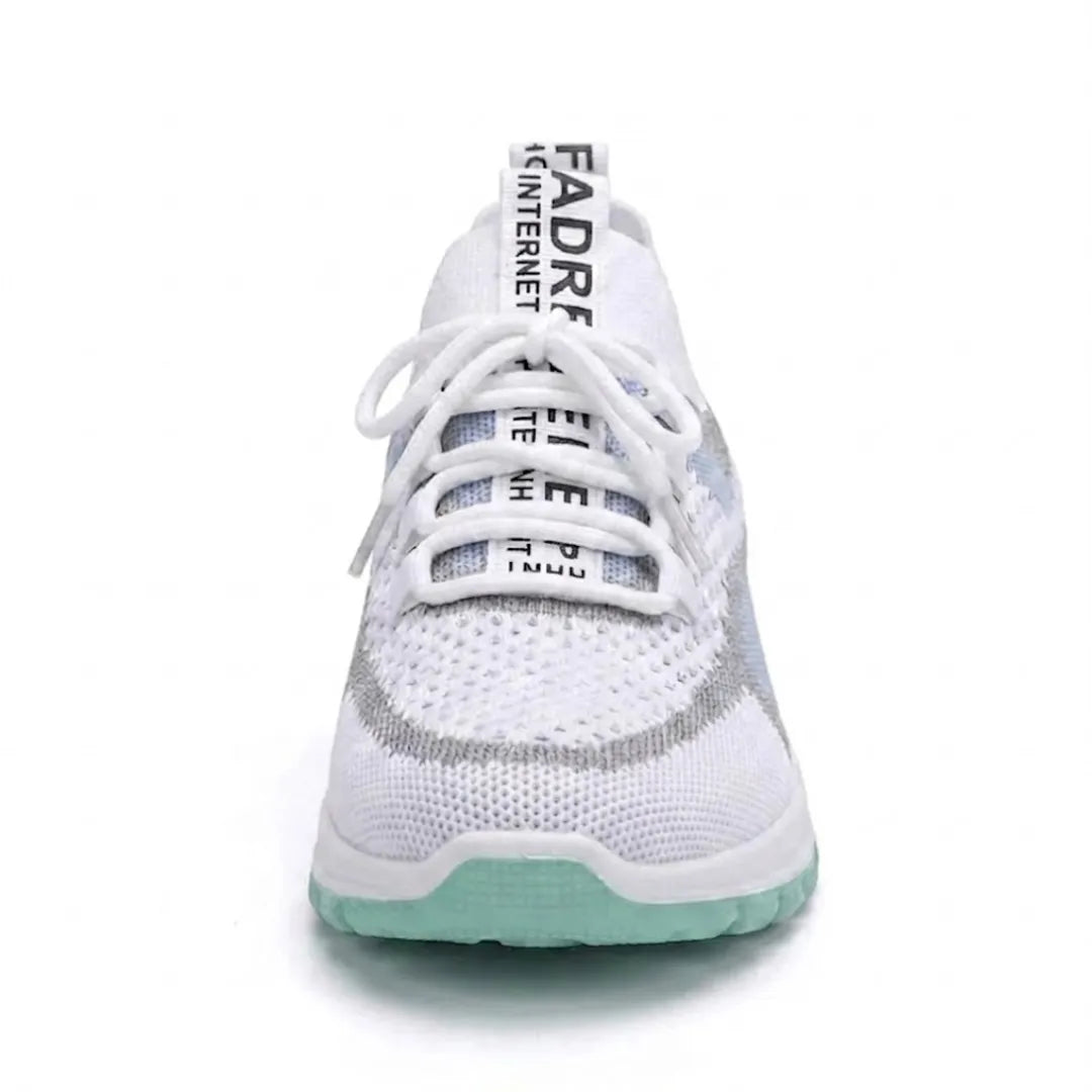Framifrån sedd vit sneaker med snörning och textilband på tungan, mintgrön sula och diskreta blå detaljer. 17