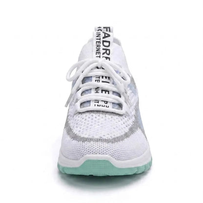 Framifrån sedd vit sneaker med snörning och textilband på tungan, mintgrön sula och diskreta blå detaljer. 17