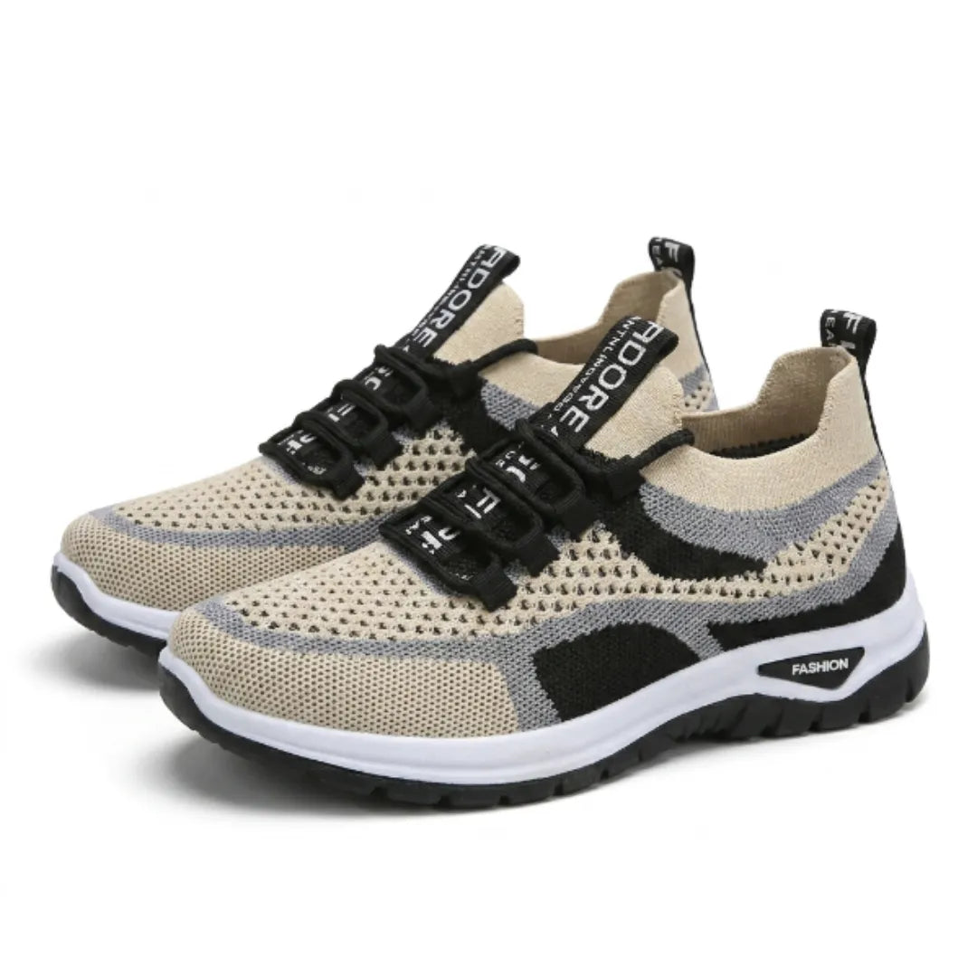 Ett par beige sneakers med genombrutet mesh, grå och svarta detaljer, snören och vit sula, sedda snett framifrån. 43