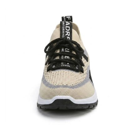 Sneakern rakt framifrån med beige mesh, svarta snören, grå och svarta fält samt dragflik med tryck på hälen. 44