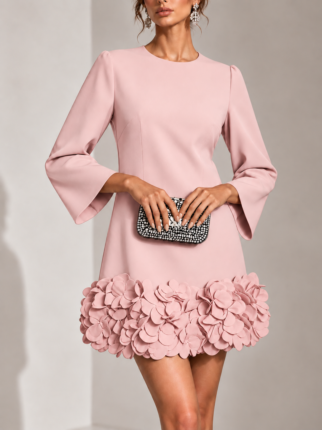 Rosa klänning i närbild framifrån med rund halsringning, utsvängda ärmar och en fyllig kant av tredimensionella blommor. 9