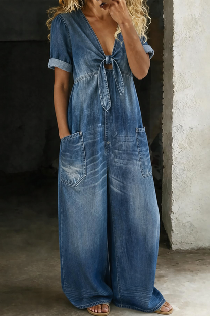Modell bär overallen i mellanblå tvättad denim, sedd framifrån med knytning och stora fickor 1