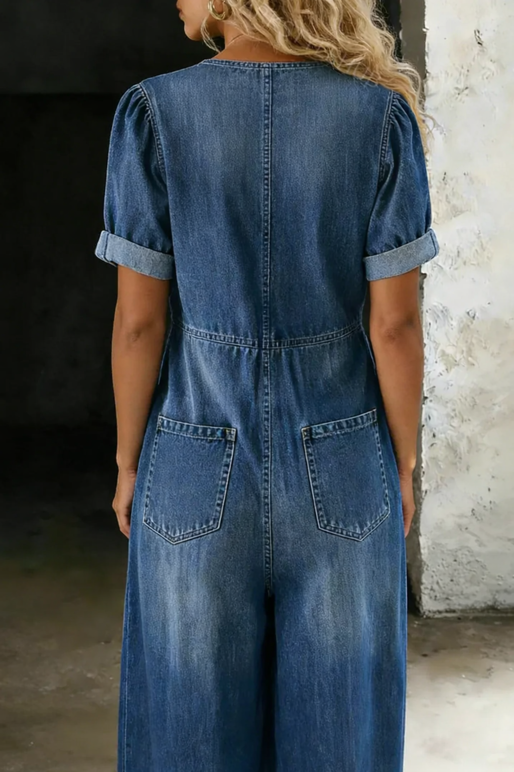 Overallens baksida i blå denim med två bakfickor, uppvikta korta ärmar och sömmar i ryggen 5