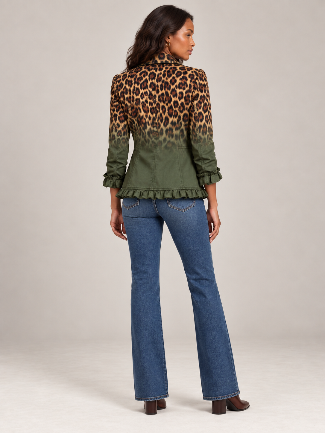 Modell bakifrån i grön blazer med leopardmönster överst, volang i nederkant och på ärmslut, med utsvängda jeans. 7