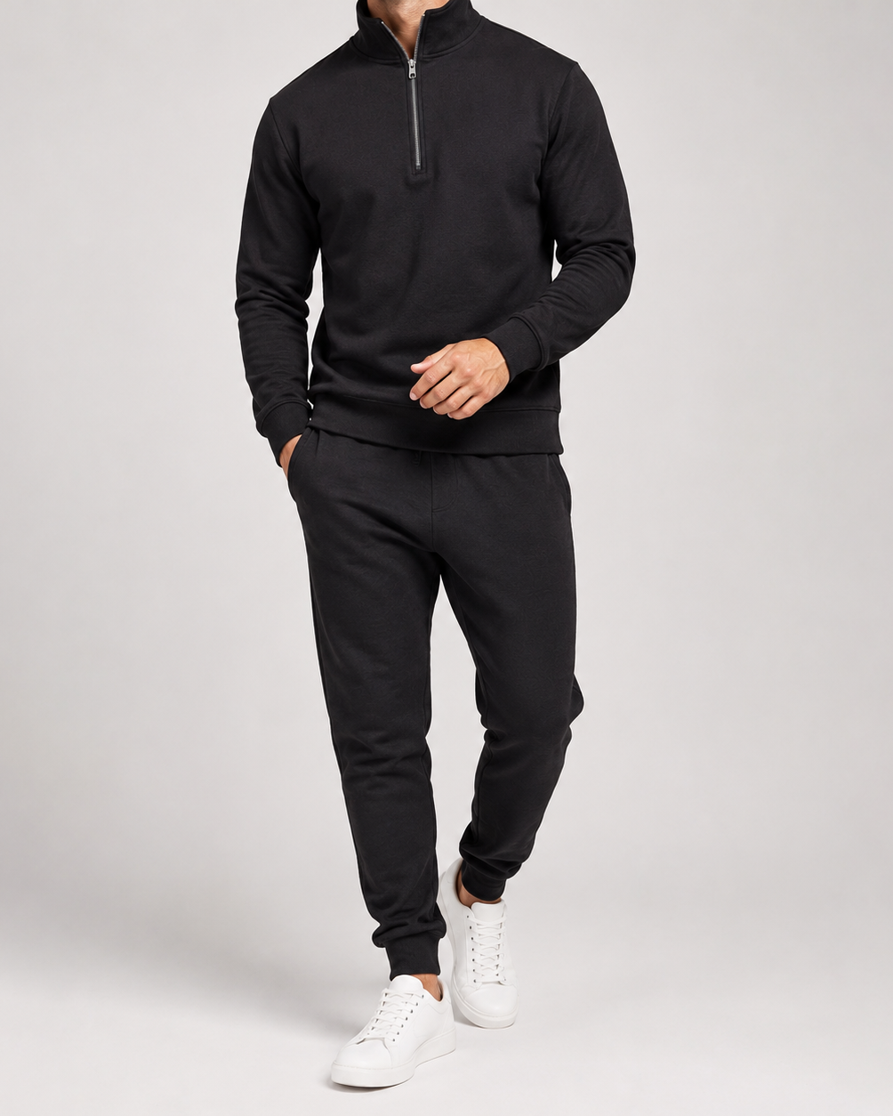 Svart set med halvdragkedja och joggingbyxor, buret av en man med vita sneakers 3