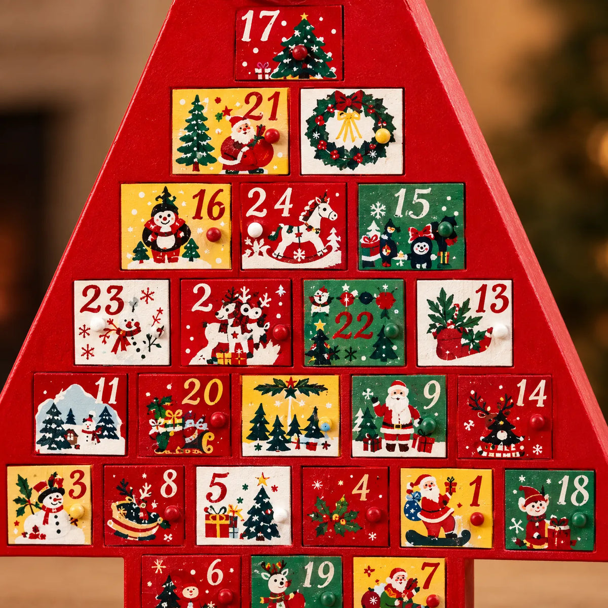 Närbild på adventskalenderns små lådor med handmålade jultomtar, snögubbar och julgranar och runda knoppar som handtag. 3
