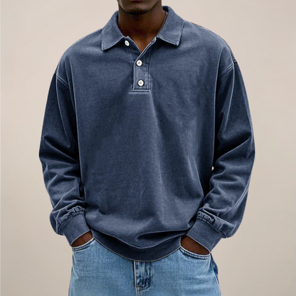 Man i marinblå långärmad tröja med krage och knappslå, händerna i fickorna på jeans, framifrån. 5