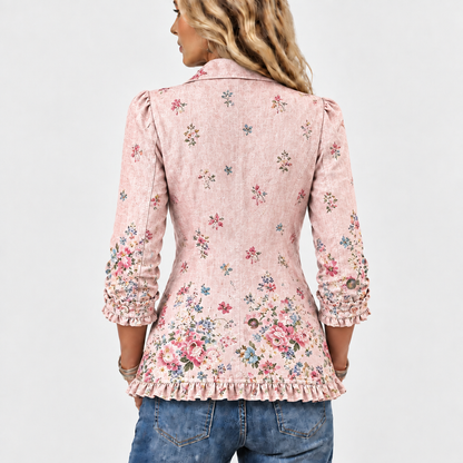 Jackan bakifrån på en modell, med spridda blommönster, tätare blommor nedtill och volang vid fållen och ärmslutet. 5