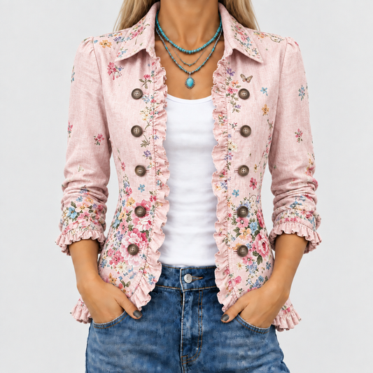 Närbild av den rosa blommiga jackan med volangkanter och stora knappar, öppen över ett vitt linne och jeans. 1