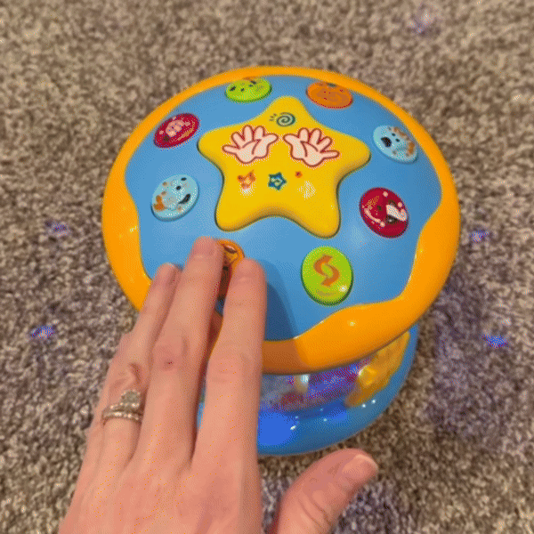 Buntes, drehbares Babyspielzeug mit Lichtern auf Teppichboden, interaktive Lernhilfe.