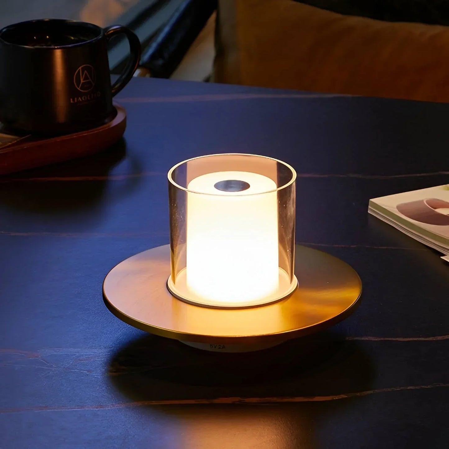 Moderne LED-Tischlampe, goldfarben, zylindrisch, auf dunklem Tisch, stimmungsvolle Beleuchtung.
