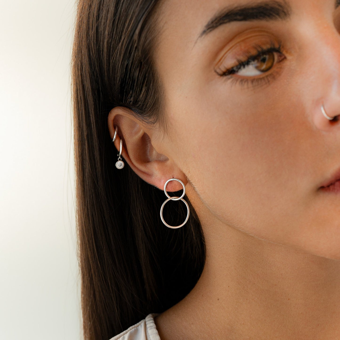Frau mit silbernen Ohrringen, Kreolen-Design, Nahaufnahme, modischer Schmuck, minimalistisch.