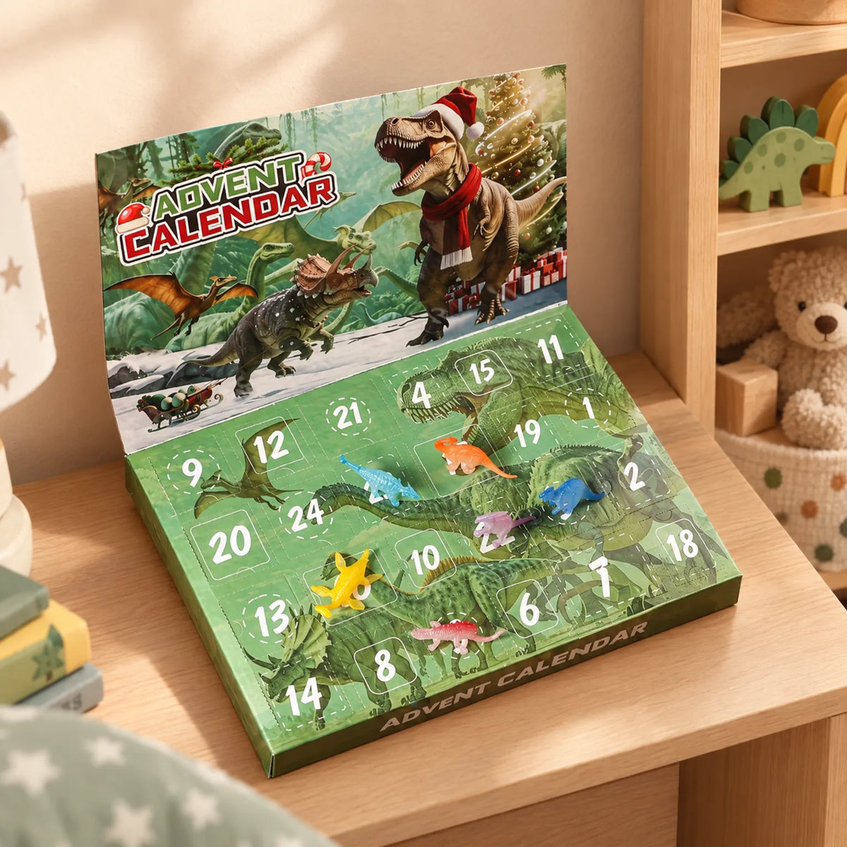 Grön adventskalender med dinosaurier och julmotiv står uppfälld på en barnrumshylla, med några små plastdinosaurier utplacerade på luckorna. 1