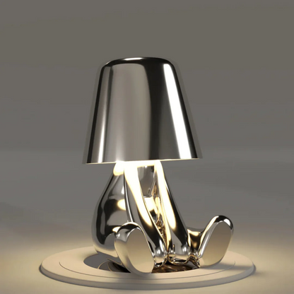 Silberne Tischlampe in Form einer sitzenden Figur, modernes Design, glänzend, dekorativ.
