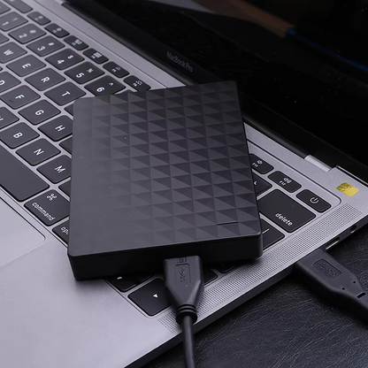 Hårddisken ligger på tangentbordet till en bärbar dator och är ansluten med en svart USB-kabel 3