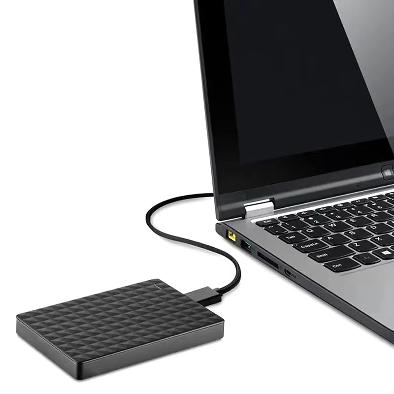Hårddisken står på bordet bredvid en öppen bärbar dator och är kopplad med en kabel till dess USB-port 5