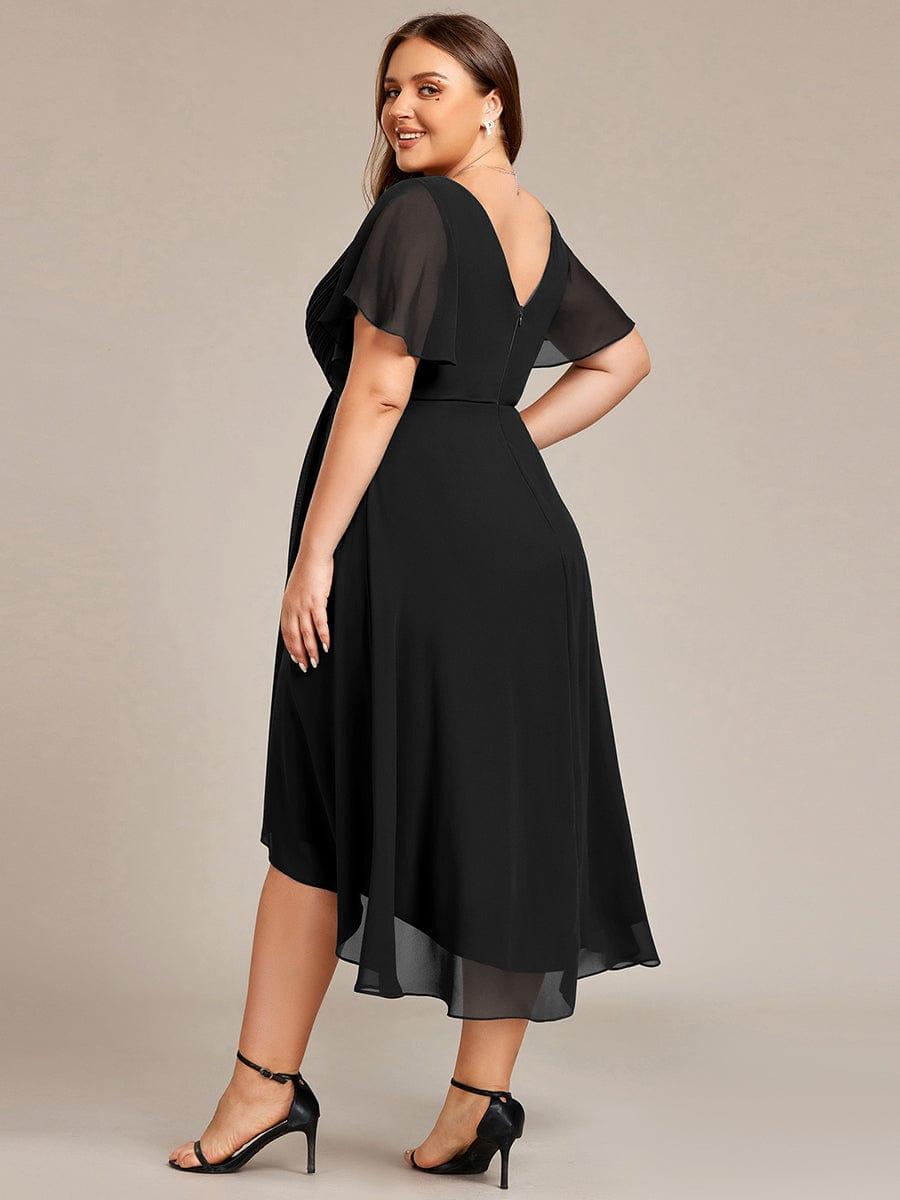 Svart klänning på plus size-modell bakifrån med V-ringad rygg, dragkedja och skira vingärmar, hon ser leende över axeln. 27