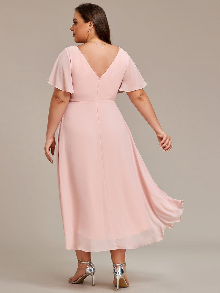 Ljusrosa klänning på plus size-modell bakifrån med V-ringad rygg, dragkedja och en längre, svepande bakkant. 32