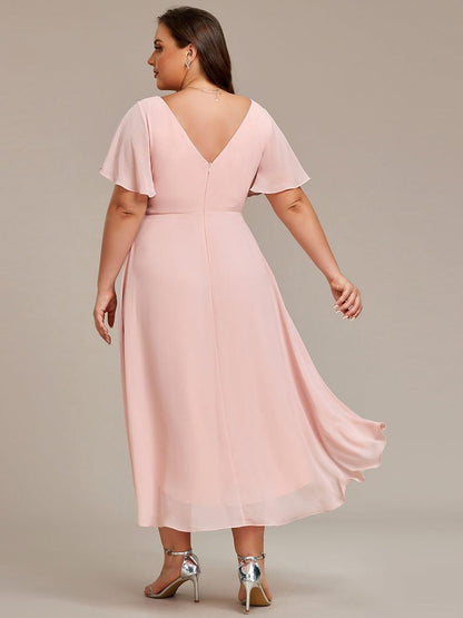Ljusrosa klänning på plus size-modell bakifrån med V-ringad rygg, dragkedja och en längre, svepande bakkant. 32