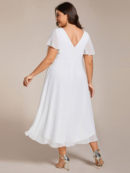 Plus size-modell i vit klänning sedd bakifrån, med V-ringad rygg, dragkedja och längre bakkant. 74