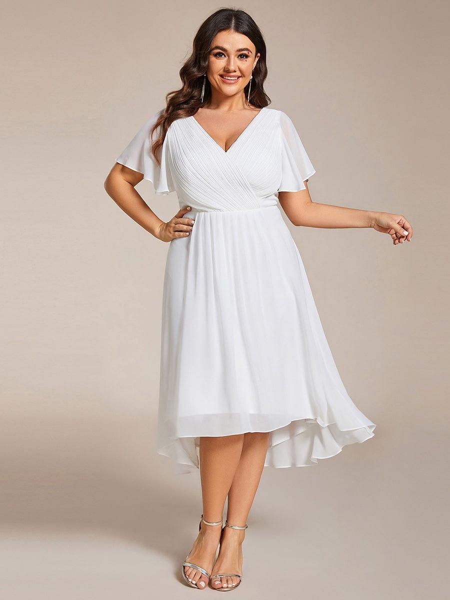 Plus size-modell i vit chiffongklänning, framifrån, med veckad V-ringning, korta ärmar och asymmetrisk fåll. 73