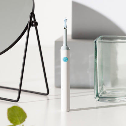 Elektrischer Ohrenreiniger, weiß, mit blauem Knopf, auf weißem Tisch, modernes Design.
