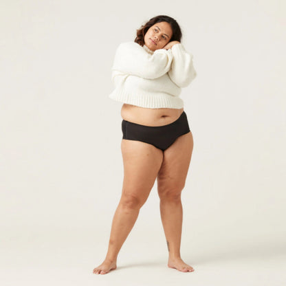 Frau in schwarzem Slip und weißem Pullover, Plus-Size-Mode, bequeme Unterwäsche.