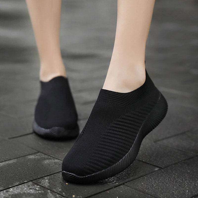 Schwarze Sneaker ohne Schnürsenkel, atmungsaktiv, rutschfest, für Damen, auf nassem Pflaster.