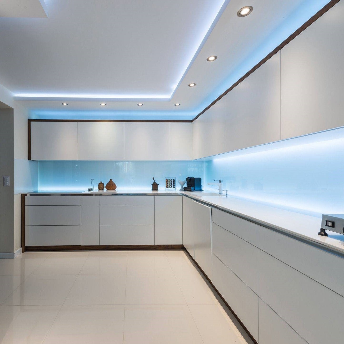 Moderne weiße Einbauküche mit LED-Beleuchtung, Hochglanzfronten und minimalistischer Gestaltung.