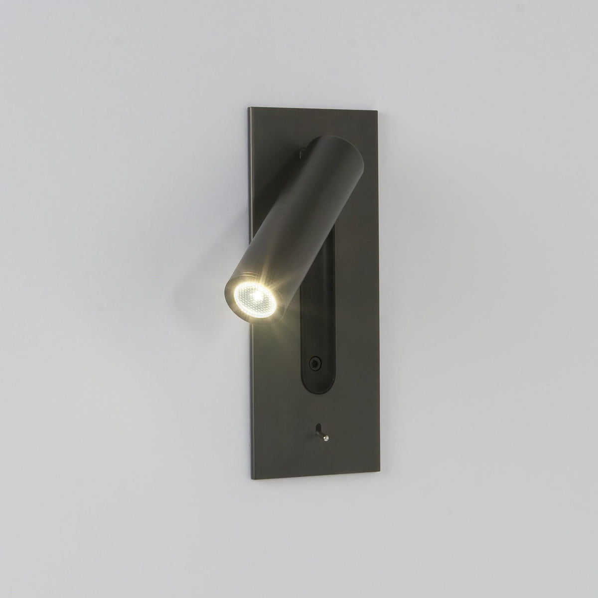 Mörk vägglampa med tänd LED-spot riktad nedåt åt vänster mot en ljus vägg 5