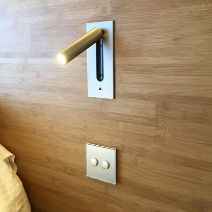 Lampa med guldfärgad cylinder på silverfärgad platta, monterad på träpanel ovanför en tvåknappsbrytare 29