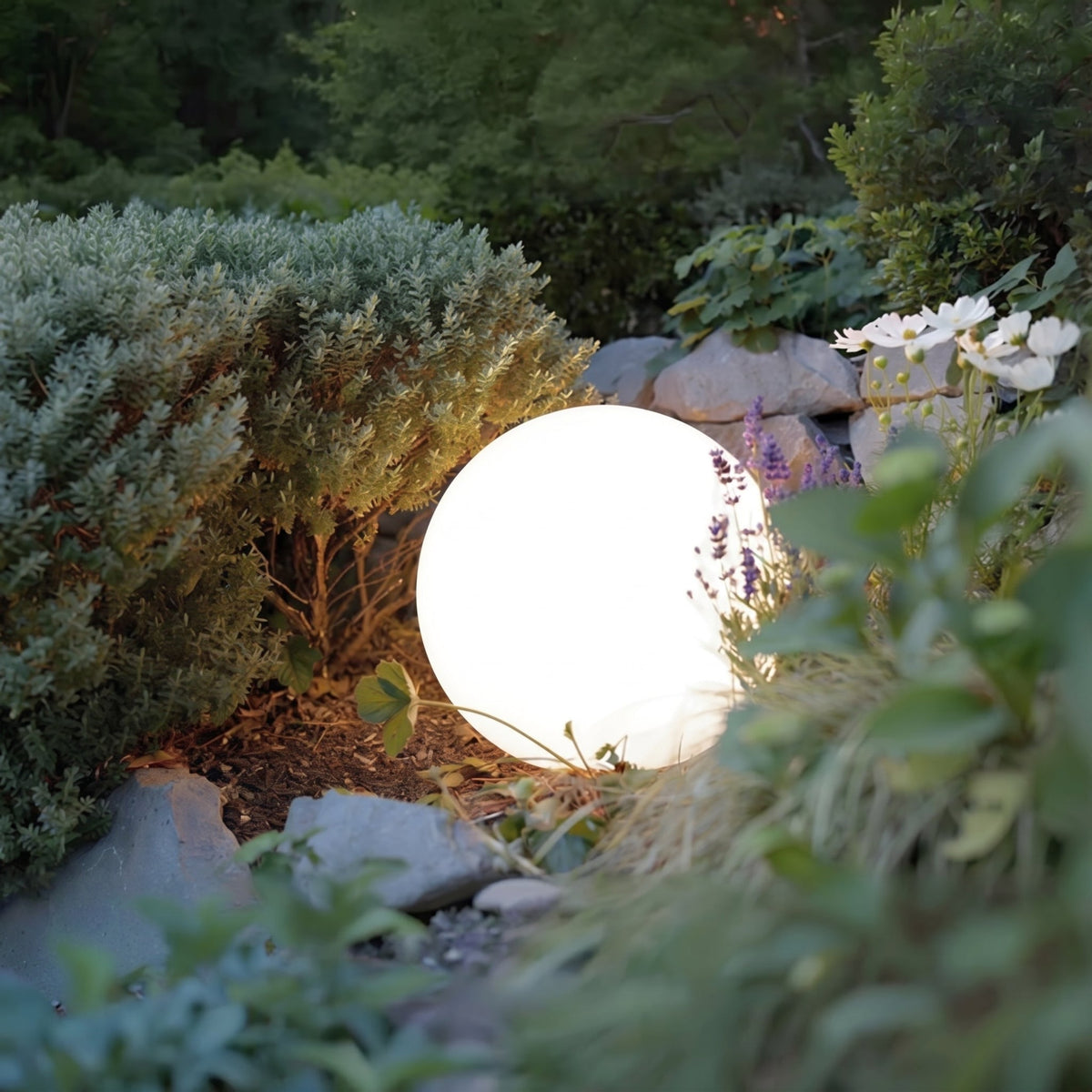 Närbild på en ensam lysande sfärlampa som sitter bland buskar, lavendel, vita blommor och stenar. 5