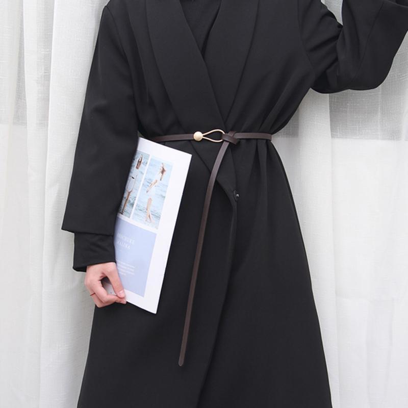 Schwarzer Mantel mit goldener Schnalle und Knotenriemen, elegantes Design, Damenmode.