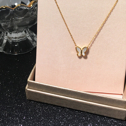 Goldene Schmetterlingskette auf rosa Hintergrund, modisch, elegant, Damenaccessoire.