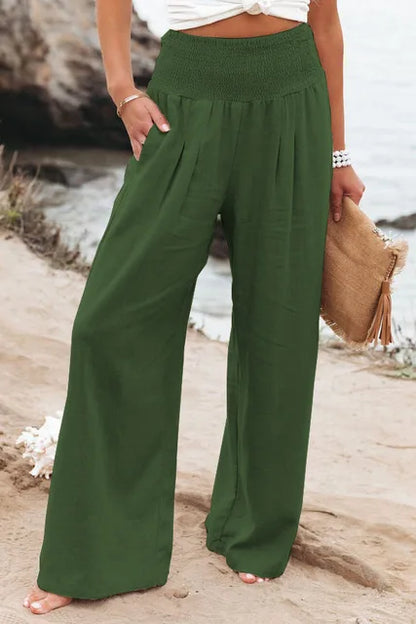 Frau in grüner Leinenhose am Strand, Sommermode, weite Passform, lässiger Stil.