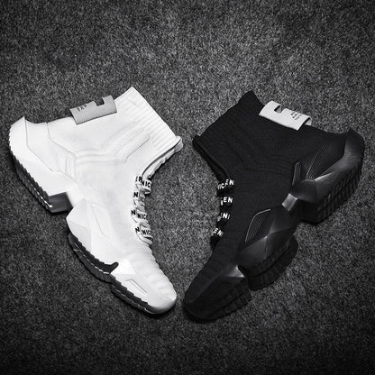 Weiße und schwarze Sneaker, gestricktes Obermaterial, rutschfeste Sohle, modisches Design.