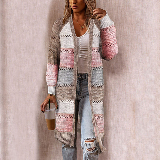 Frau trägt gestreiften Strick-Cardigan in Beige, Rosa und Grau, kombiniert mit zerrissenen Jeans.